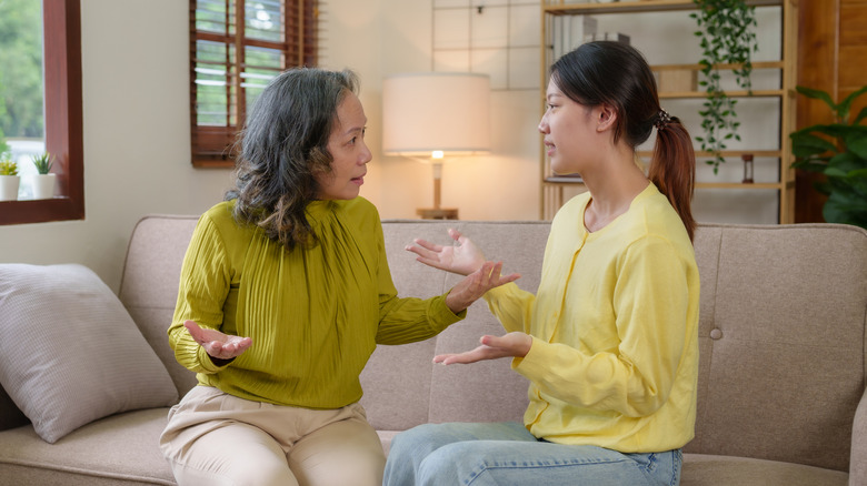 Older woman and younger woman arguing with one another while sitting on a couch