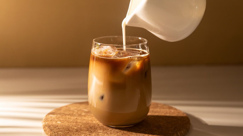 pouring milk into iced coffee
