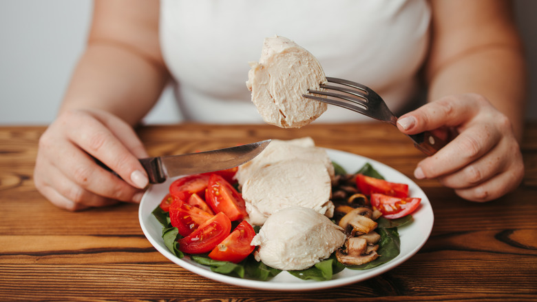 A woman eat tomatoes, chicken, spinach, and mushrooms