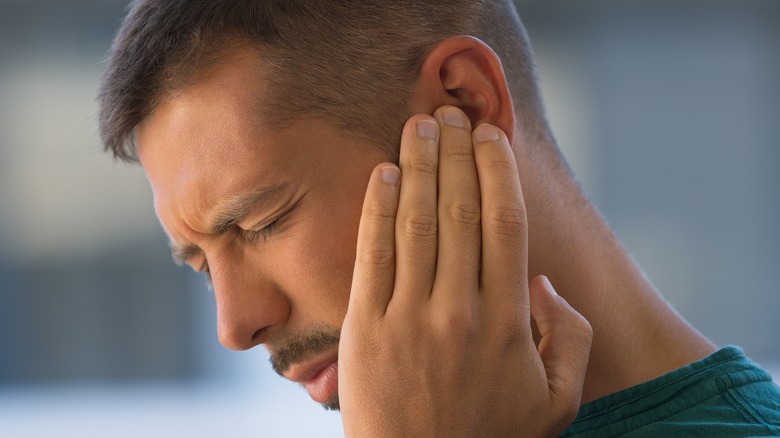 man holding ear in pain