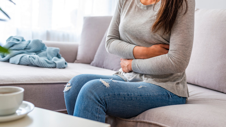 Woman with a stomachache sits on a couch
