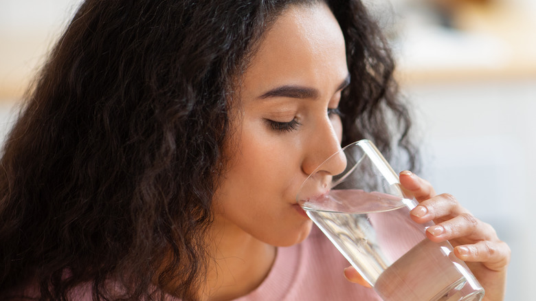 a woman drinking out of a glass of water 