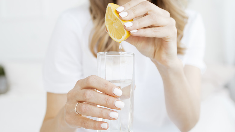 a woman squeezing a lemon into water