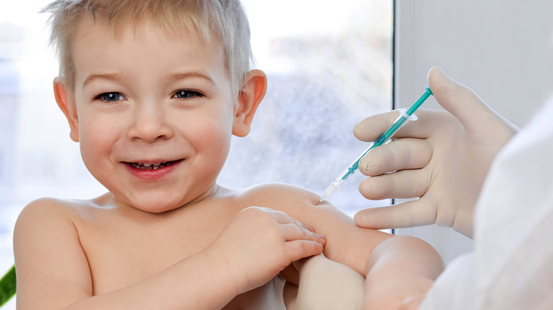 Young child smiling receiving vaccine in arm