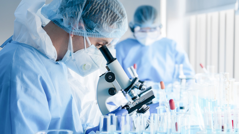 Scientists using microscope in lab
