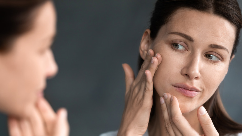 woman checking face in mirror
