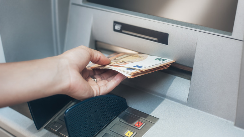 A hand accepting money from an ATM