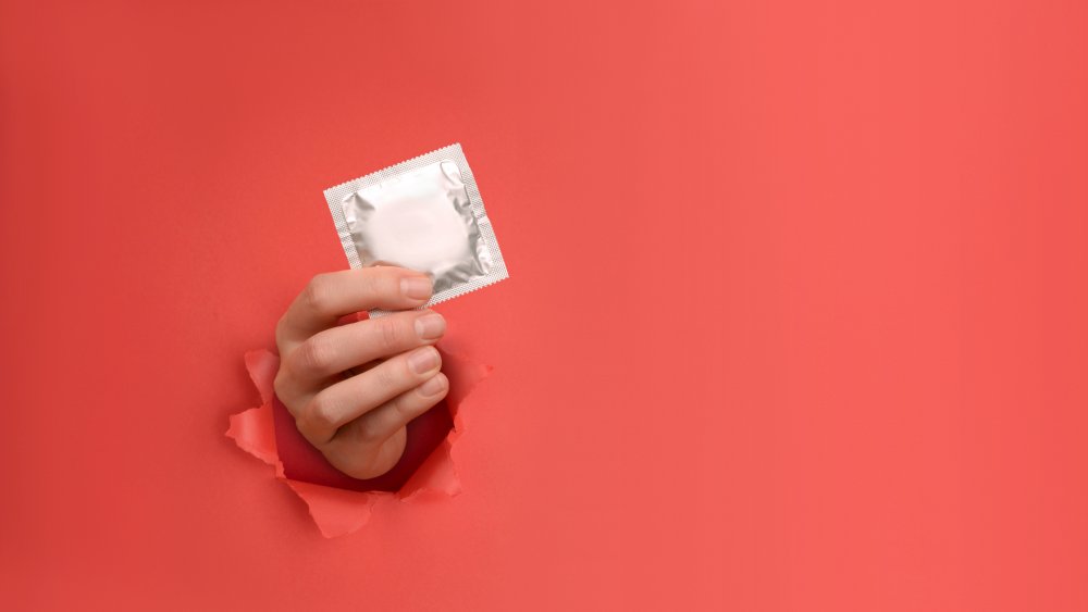 Hand holds condom, a type of birth control