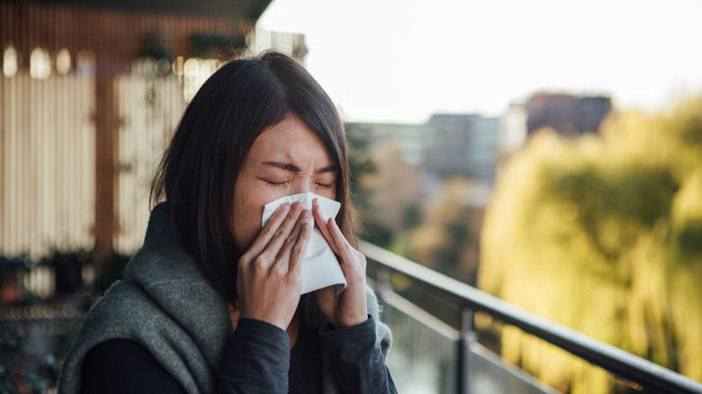Woman sneezing outside from allergies