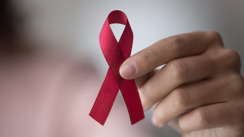person holding HIV/AIDS awareness ribbon