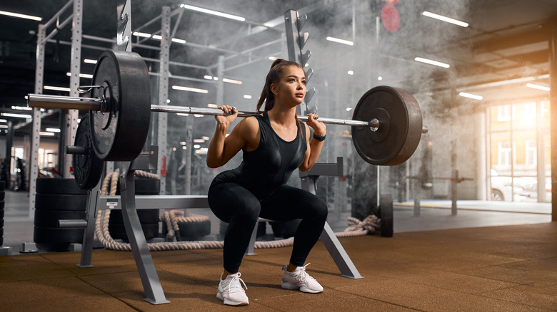 Woman doing barbell back squats