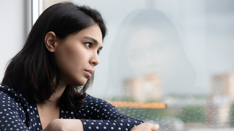 sad woman looks out window