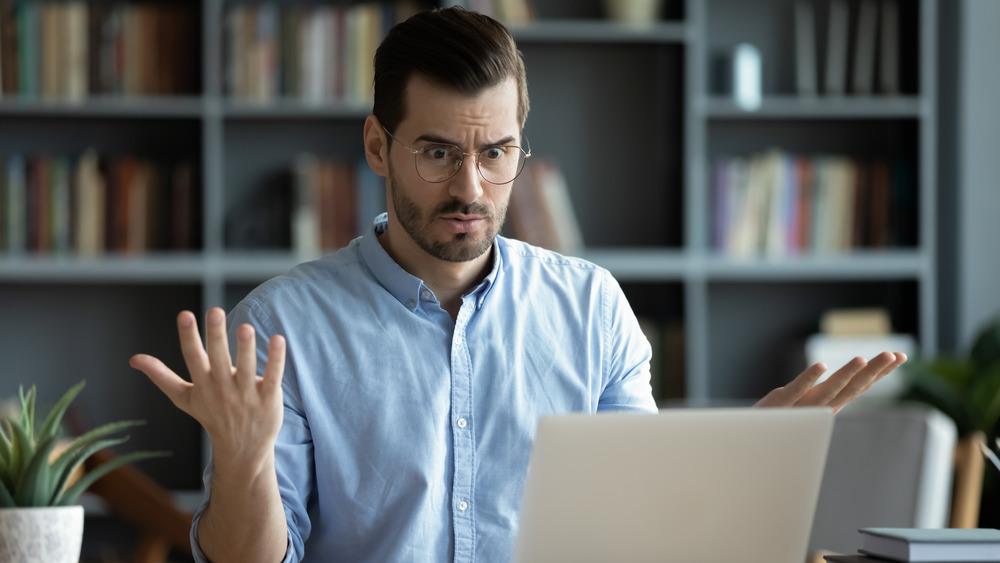 Confused man looking at his computer and shrugging