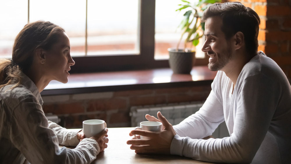 Man and woman facing each other across the table and smiling