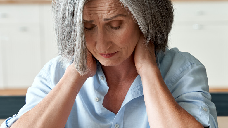 Woman at desk holding neck