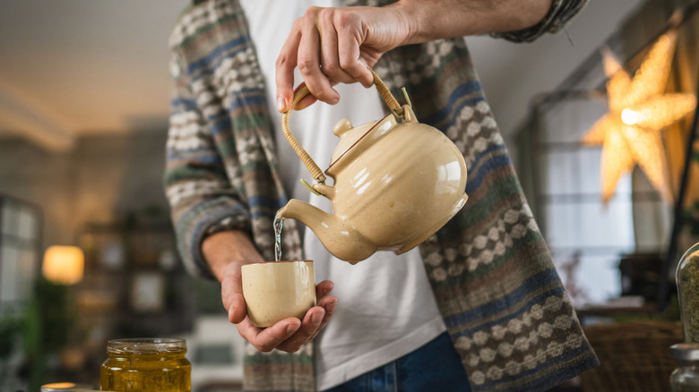 man pouring water into a teacup at home