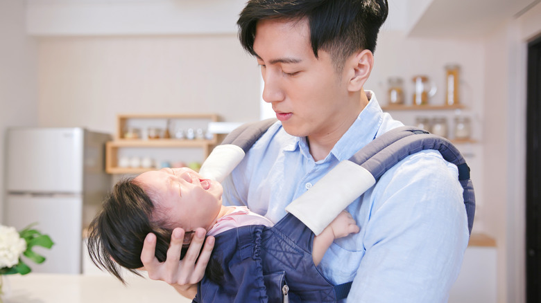 Father holding his baby in a carrier