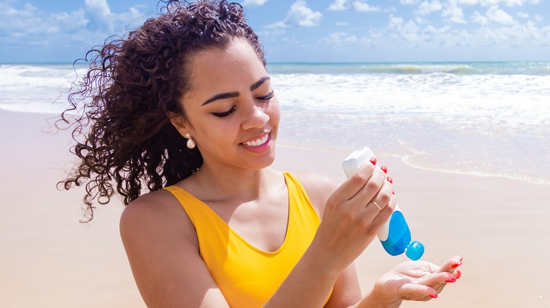 Woman at beach applying sunscreen