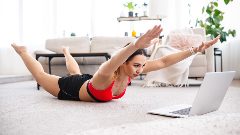 A woman does the superman exercise at home