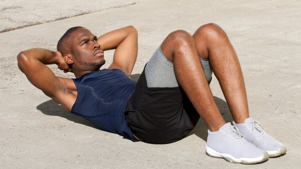 man performing sit-ups outside