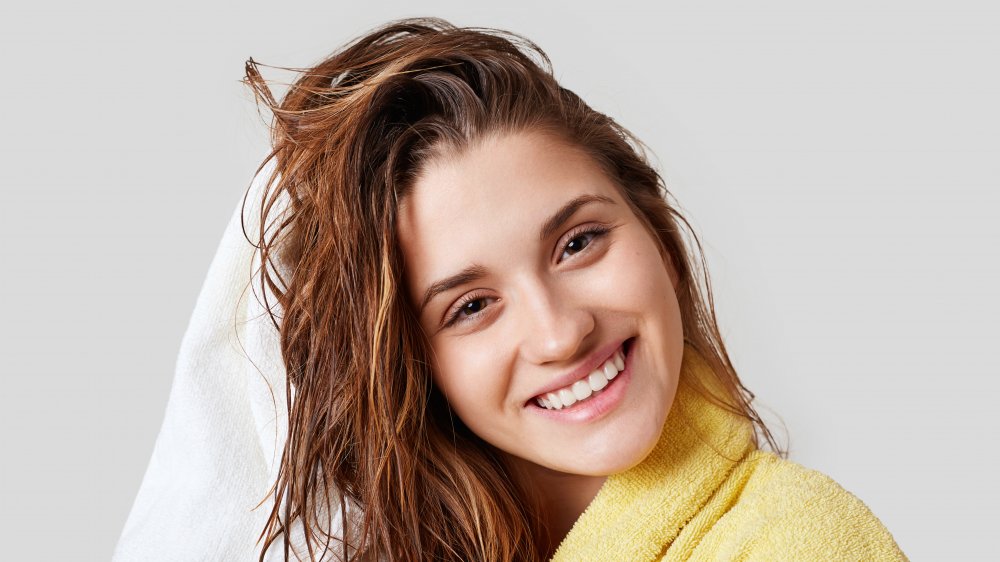 happy woman towel drying her wet hair in a yellow bathrobe 