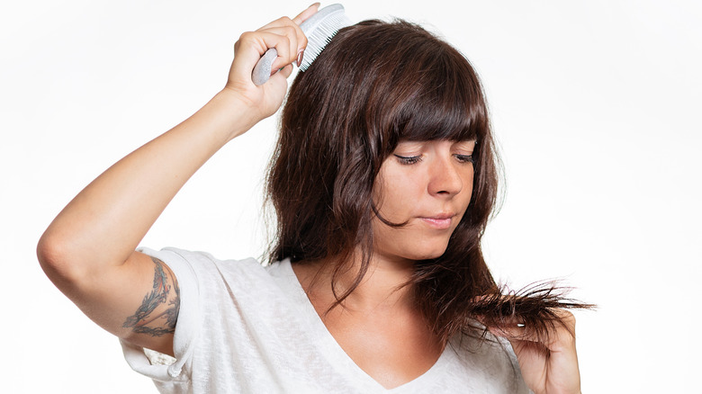 Woman brushing hair and examining split ends