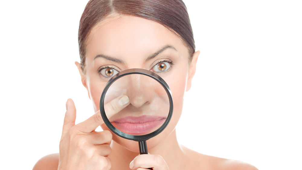 Woman with a magnifying glass on the center of her face 