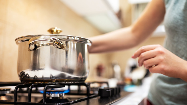 Close up of woman cooking with saucepan on the stove