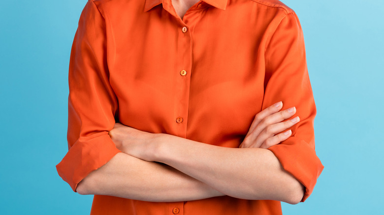A woman stands with her arms crossed 