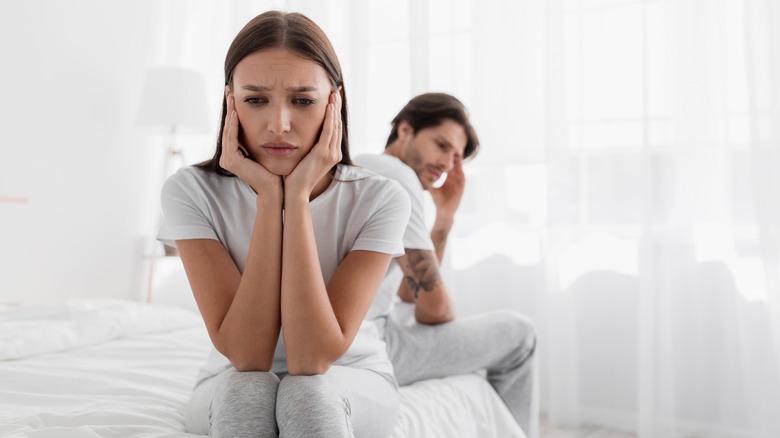 Woman and man sitting on bed