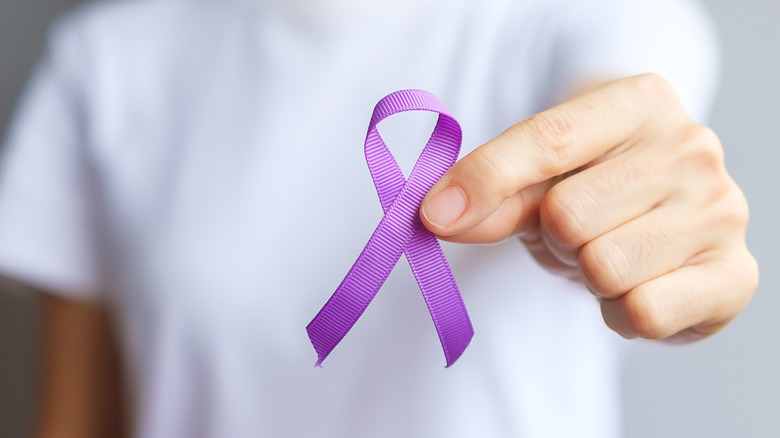 Someone holds a purple cancer ribbon