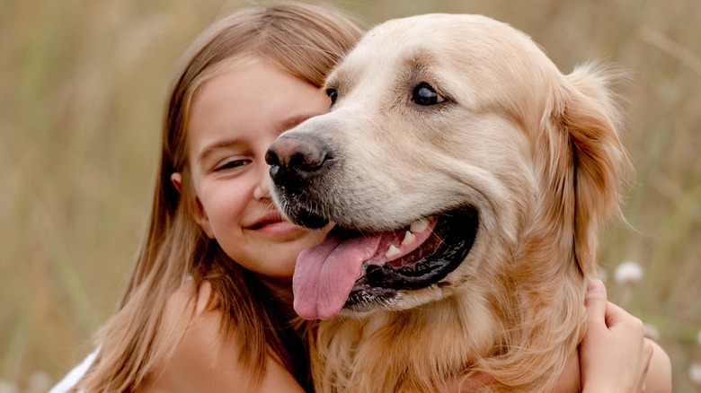 little girl hugging golden retriever