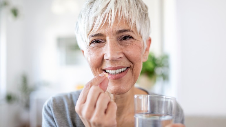 woman taking medication with a glass of water