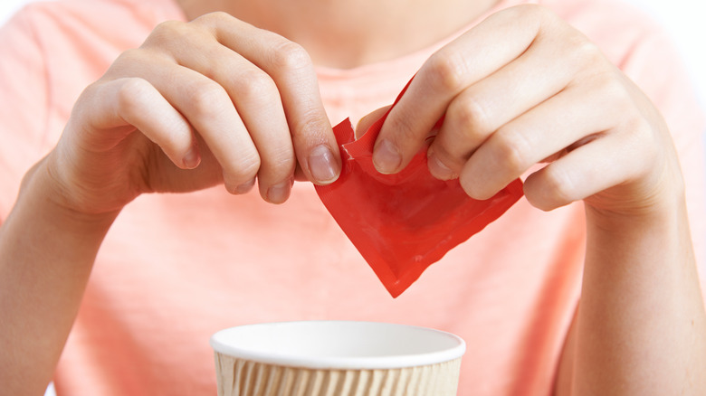 Someone adds an artificial sweetener to coffee