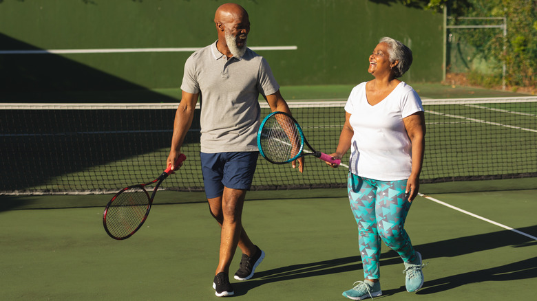 Smiling seniors on tennis court