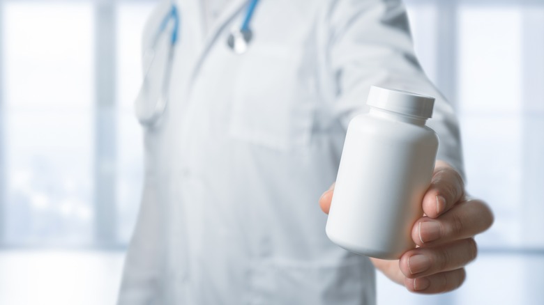 A doctor holds an unmarked pill bottle