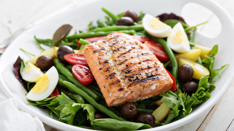 Grilled salmon on a bed of greens with eggs