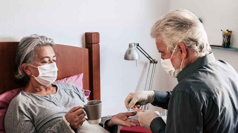 Woman in bed getting medicine from carer