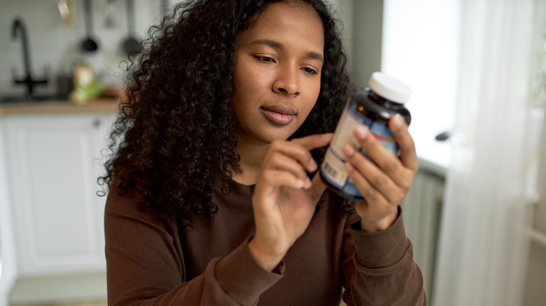 woman looking at bottle instructions