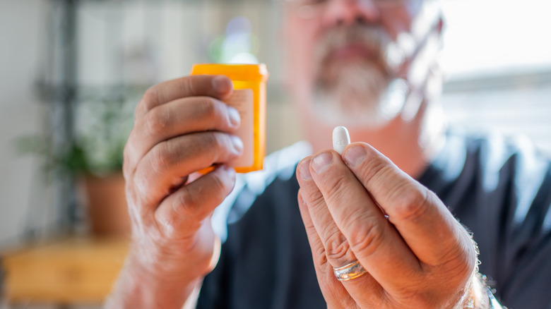 man looking at prescription pill