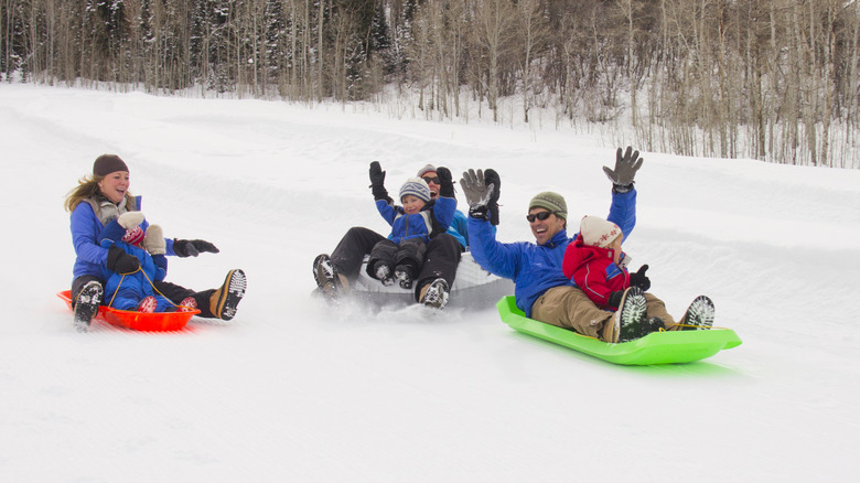 Parents with young children sledding in the snow