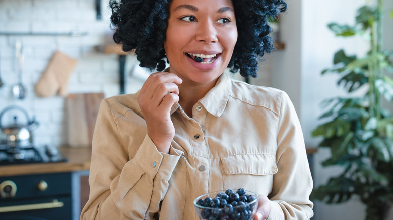 A woman enjoying a bowl of blueberries