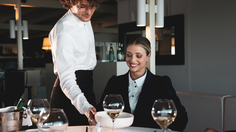 Waiter serving an expensive meal to a woman