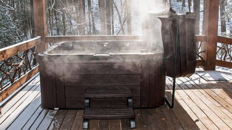 steaming hot tub on wooden deck with snow