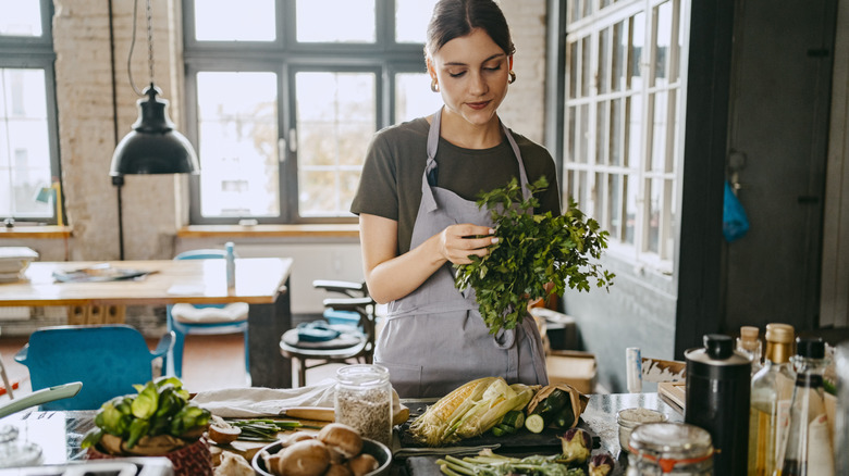 A woman sorting through a variety of vegetables in her kitchen