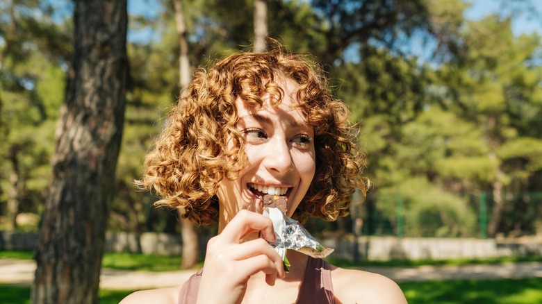 Smiling woman holding protein bar