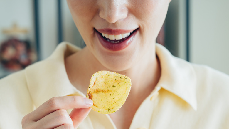 young woman holding a potato chip in her hand