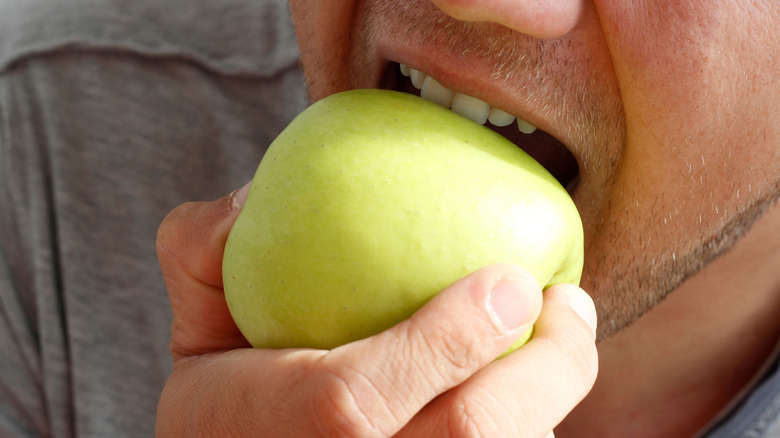 man's mouth biting into an apple