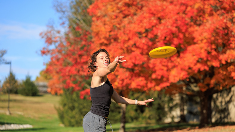 A woman throwing a plastic disc to another person