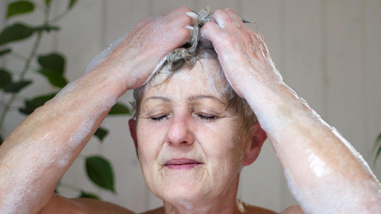 senior woman washing hair in a bathtub